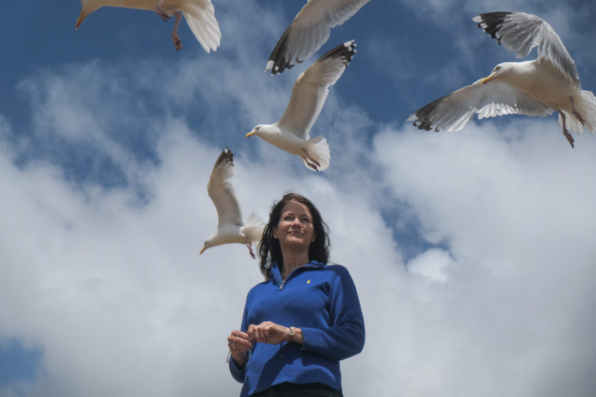 Lee Baker standing with seagulls above her head